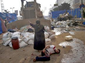 An Egyptian woman protects an injured youth from a security forces bulldozer dismantling a protest camp